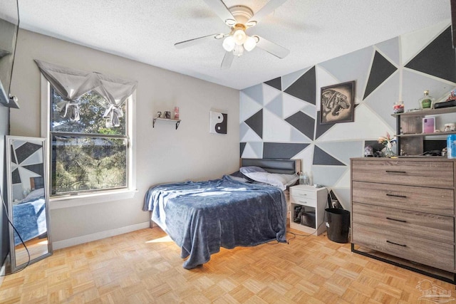 bedroom with a textured ceiling, light parquet floors, and ceiling fan