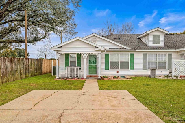 view of front of property featuring covered porch, a shingled roof, a front lawn, and fence