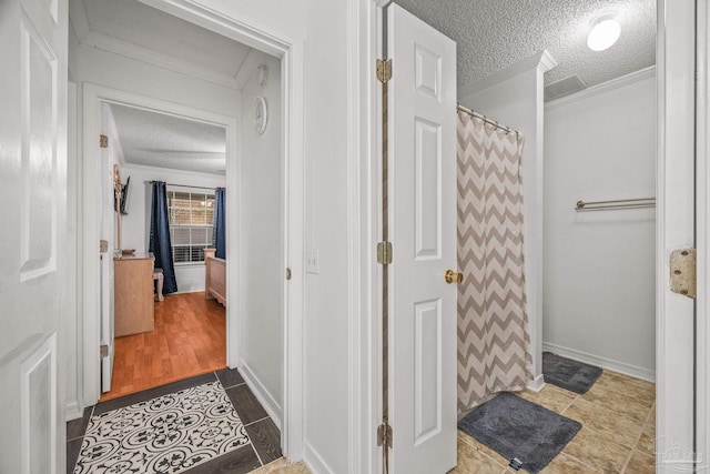 full bathroom with a shower with shower curtain, wood finished floors, baseboards, ornamental molding, and a textured ceiling