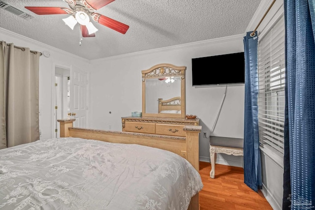 bedroom featuring visible vents, wood finished floors, and ornamental molding