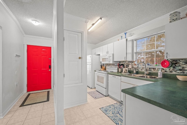 kitchen with dark countertops, crown molding, white appliances, white cabinetry, and a sink