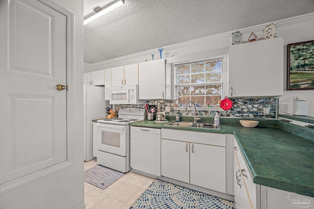 kitchen with dark countertops, ornamental molding, white appliances, white cabinetry, and a sink