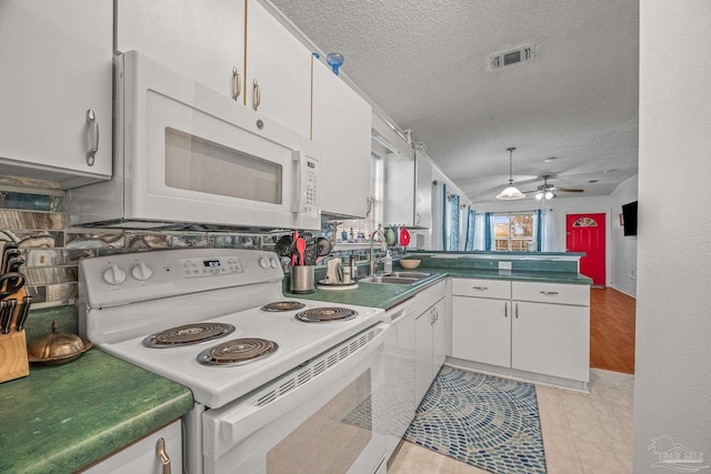 kitchen with white appliances, visible vents, a peninsula, a sink, and white cabinetry