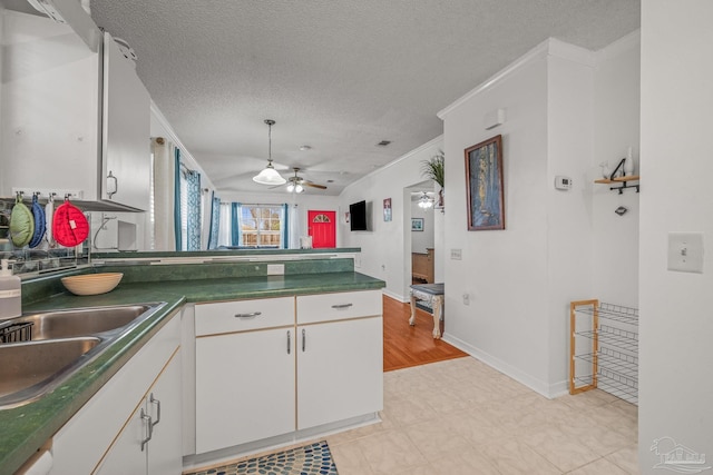 kitchen featuring dark countertops, a peninsula, white cabinets, a textured ceiling, and a sink