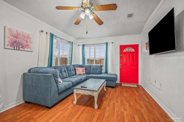 living area with visible vents, ornamental molding, and light wood finished floors