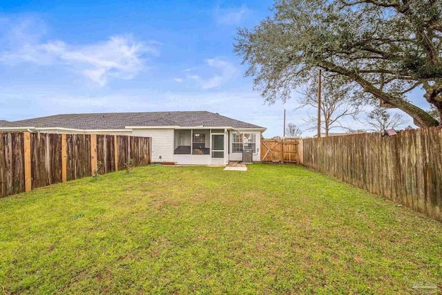 back of property with a lawn, a fenced backyard, and a sunroom