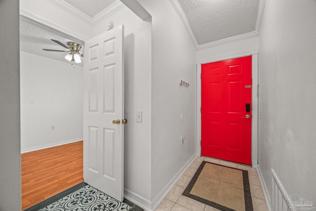 tiled foyer with baseboards, a textured ceiling, crown molding, and ceiling fan