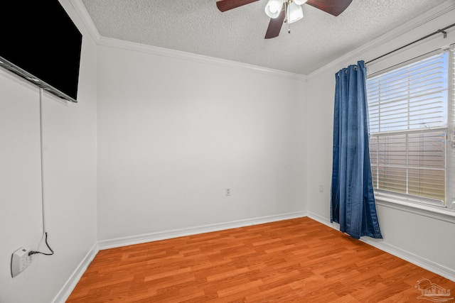 spare room featuring crown molding, baseboards, light wood finished floors, and a textured ceiling