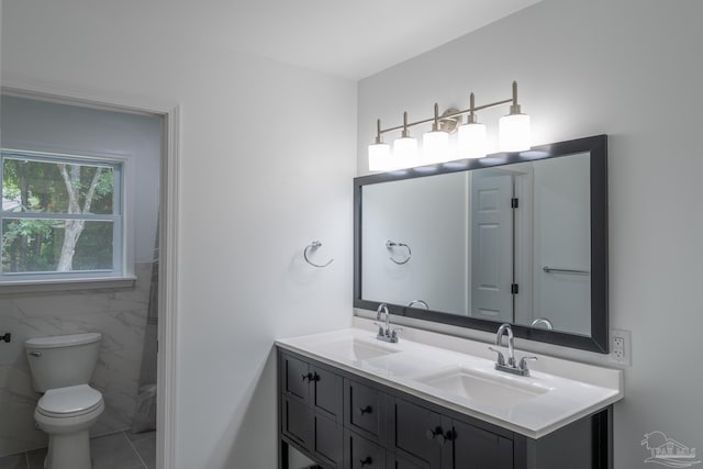 bathroom featuring tile patterned floors, vanity, toilet, and tile walls