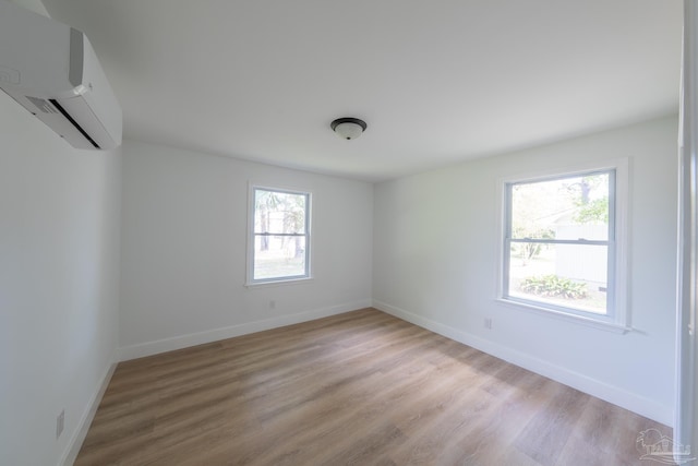 spare room featuring a wall mounted air conditioner and light wood-type flooring