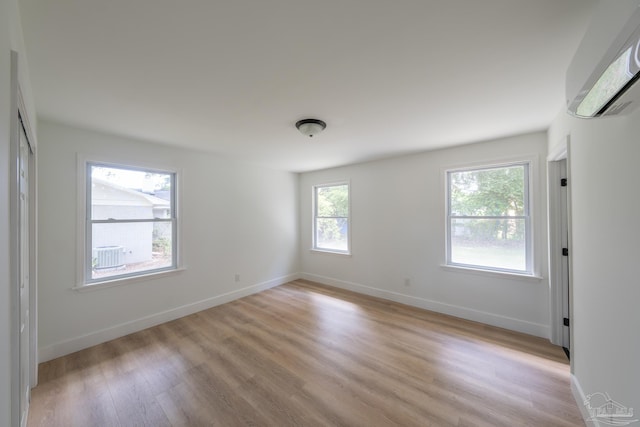 unfurnished room with a wall mounted AC and light hardwood / wood-style floors