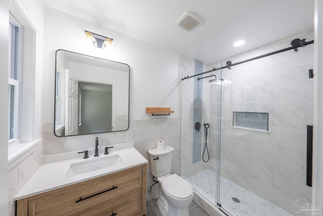 bathroom with vanity, tile walls, toilet, and walk in shower