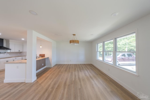 unfurnished living room with an inviting chandelier and light wood-type flooring