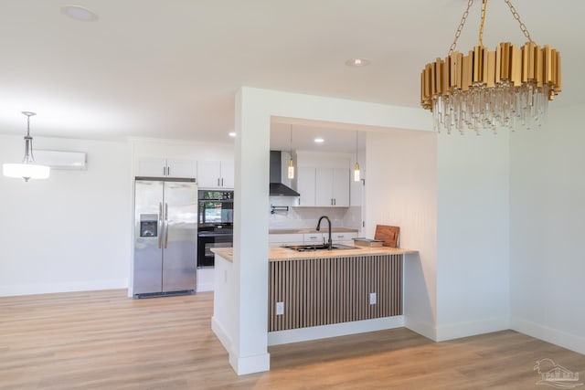 kitchen with wall chimney range hood, sink, white cabinets, stainless steel fridge with ice dispenser, and decorative backsplash