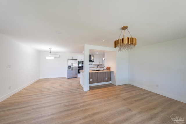 unfurnished living room with sink, light hardwood / wood-style floors, and a chandelier