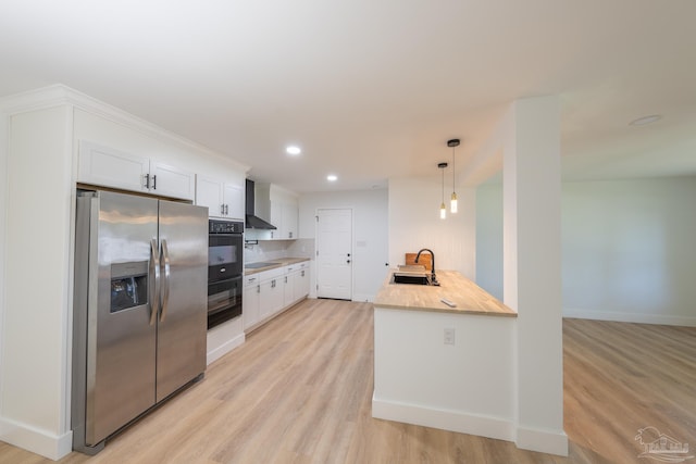 kitchen with sink, wall chimney range hood, white cabinetry, black appliances, and decorative light fixtures