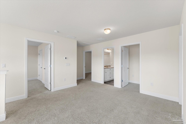 unfurnished bedroom featuring ensuite bathroom and light colored carpet