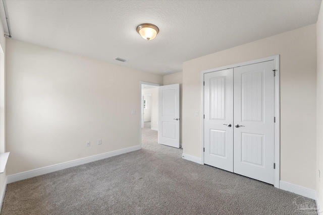 unfurnished bedroom with carpet, a textured ceiling, and a closet