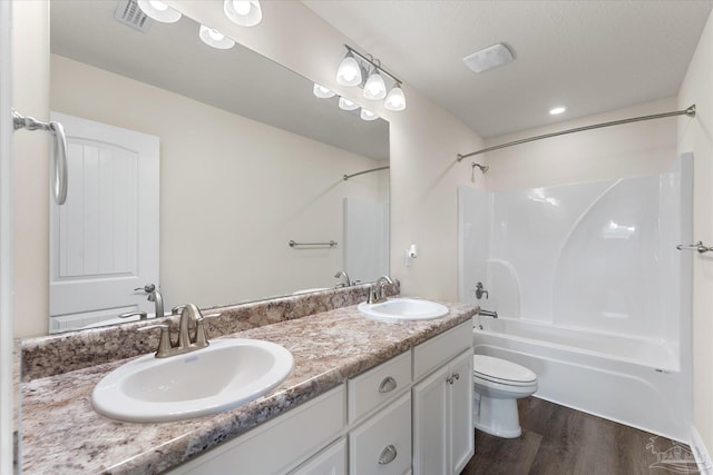 full bathroom with shower / bathing tub combination, hardwood / wood-style floors, a textured ceiling, toilet, and vanity