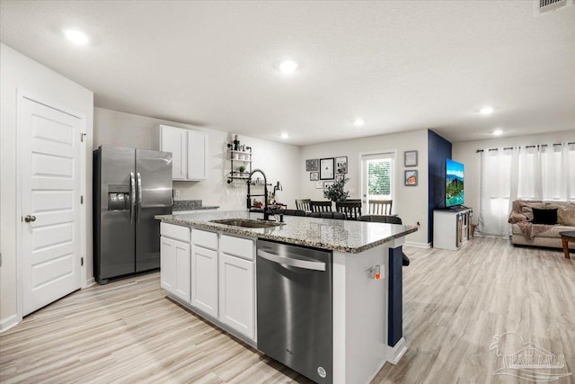 kitchen featuring stainless steel appliances, light wood-style flooring, a kitchen island with sink, and a sink