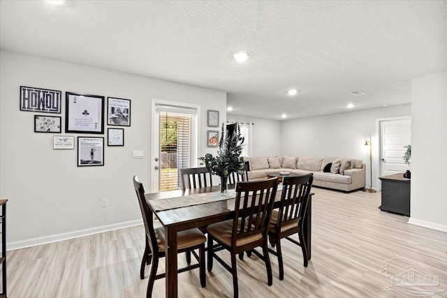 dining area with light wood-style flooring, a textured ceiling, baseboards, and recessed lighting