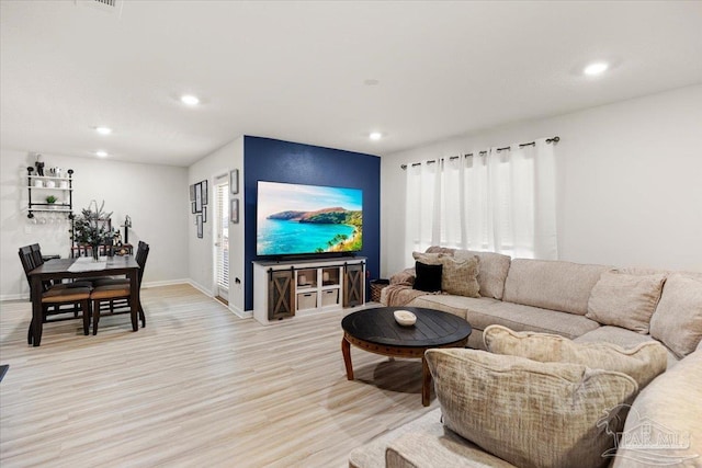 living area with baseboards, recessed lighting, and light wood-type flooring
