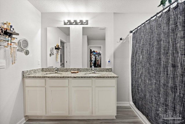 bathroom with a sink, double vanity, baseboards, and wood finished floors