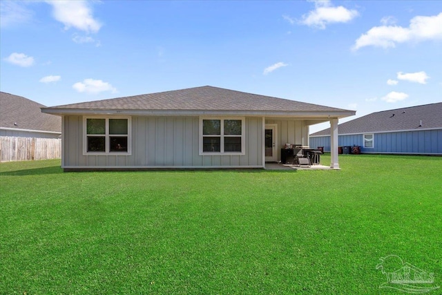 back of house featuring a lawn, board and batten siding, fence, a patio, and roof with shingles