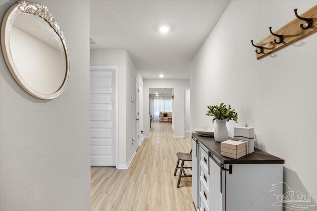 hall with light wood finished floors, baseboards, and recessed lighting