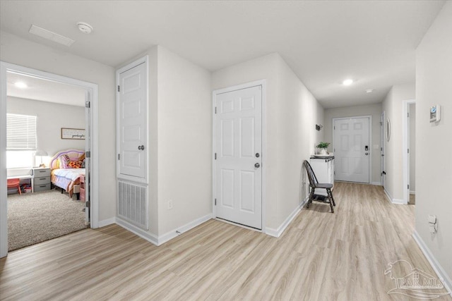 corridor with light wood finished floors, baseboards, and recessed lighting