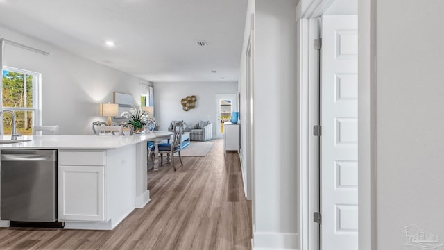 9869 Starling Dr, Pensacola, FL 32506 - kitchen with dishwasher, open floor plan, a sink, light wood finished floors, and white cabinets