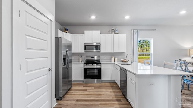 9869 Starling Dr, Pensacola, FL 32506 - kitchen with appliances with stainless steel finishes, a sink, a peninsula, light wood-type flooring, and recessed lighting