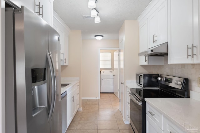 kitchen featuring under cabinet range hood, tasteful backsplash, stainless steel appliances, white cabinets, and washer / dryer