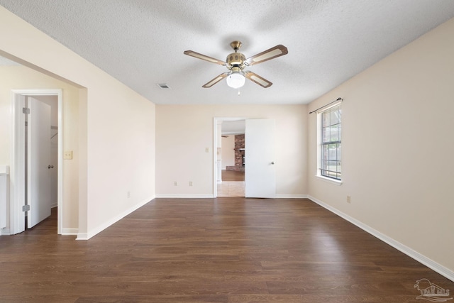 empty room with baseboards, visible vents, ceiling fan, dark wood-type flooring, and a textured ceiling