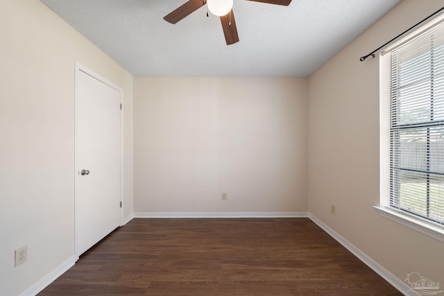 unfurnished room featuring a wealth of natural light, dark wood finished floors, baseboards, and a ceiling fan