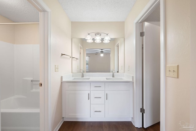 full bathroom with a sink, a textured ceiling, wood finished floors, and double vanity