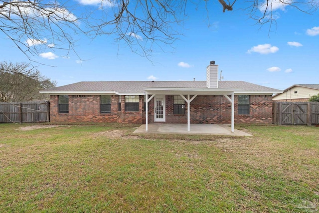 back of property with a yard, brick siding, a fenced backyard, and a patio area