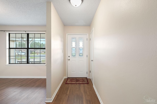 doorway featuring a textured ceiling, baseboards, and wood finished floors