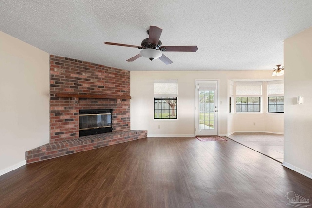 unfurnished living room with a fireplace, a textured ceiling, ceiling fan, and wood finished floors