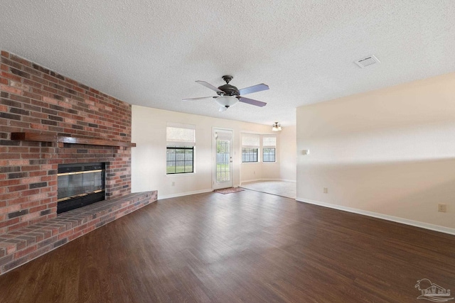 unfurnished living room featuring visible vents, baseboards, ceiling fan, a fireplace, and wood finished floors