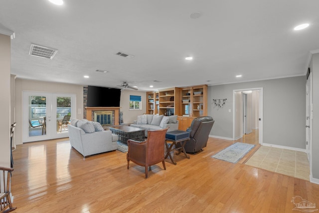 living room featuring light wood-style floors, a brick fireplace, visible vents, and ornamental molding