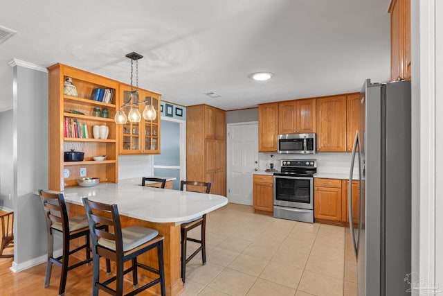 kitchen featuring appliances with stainless steel finishes, a breakfast bar, brown cabinets, and a peninsula