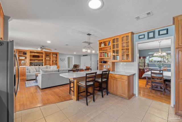 kitchen featuring a peninsula, stainless steel fridge, visible vents, and light tile patterned flooring