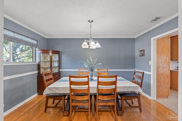 dining room featuring an inviting chandelier, visible vents, wood finished floors, and ornamental molding