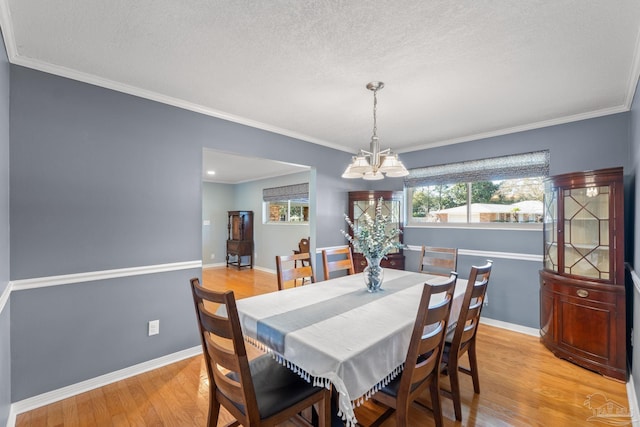 dining area with a chandelier, a textured ceiling, baseboards, light wood-style floors, and crown molding