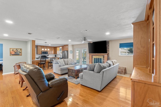 living area featuring visible vents, light wood-type flooring, and a wealth of natural light