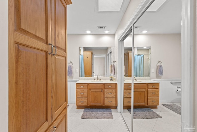 full bath with wainscoting, visible vents, a sink, and tile patterned floors