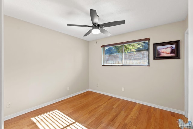 spare room with a ceiling fan, light wood-style flooring, and baseboards