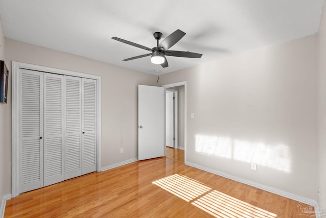 unfurnished bedroom featuring light wood-type flooring, a closet, ceiling fan, and baseboards