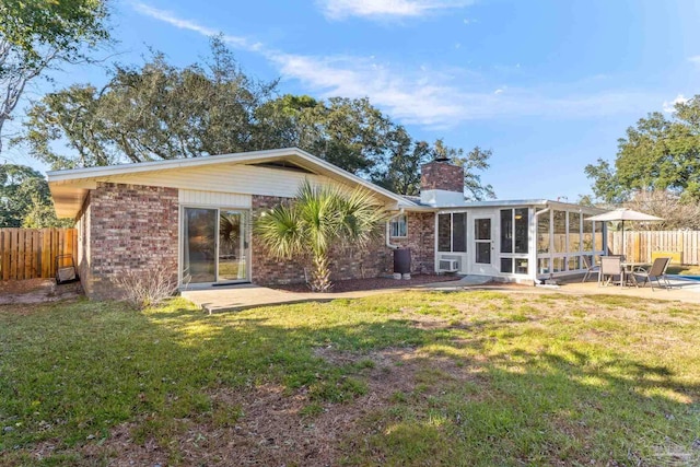 rear view of house with a lawn, a chimney, fence, and a sunroom